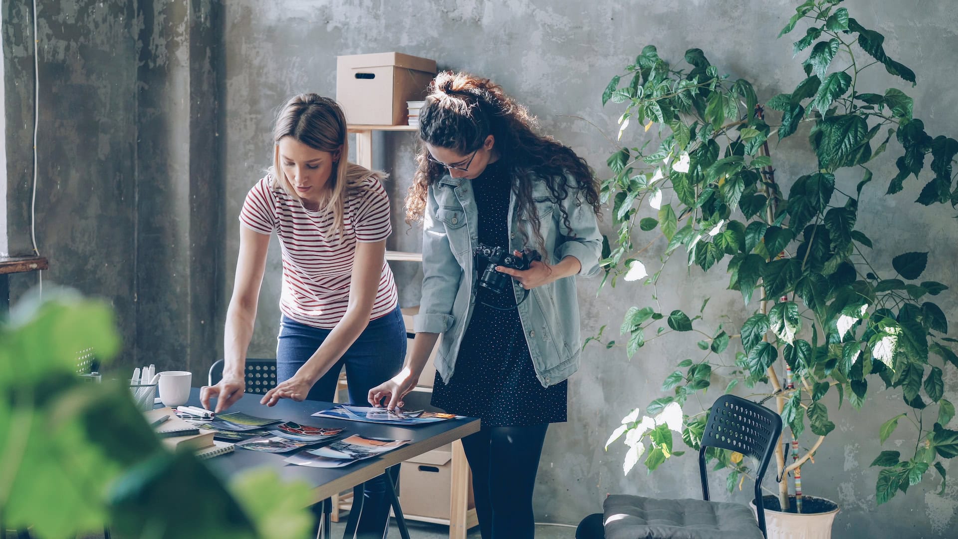 two young women creatives looking at photos laid out on a table